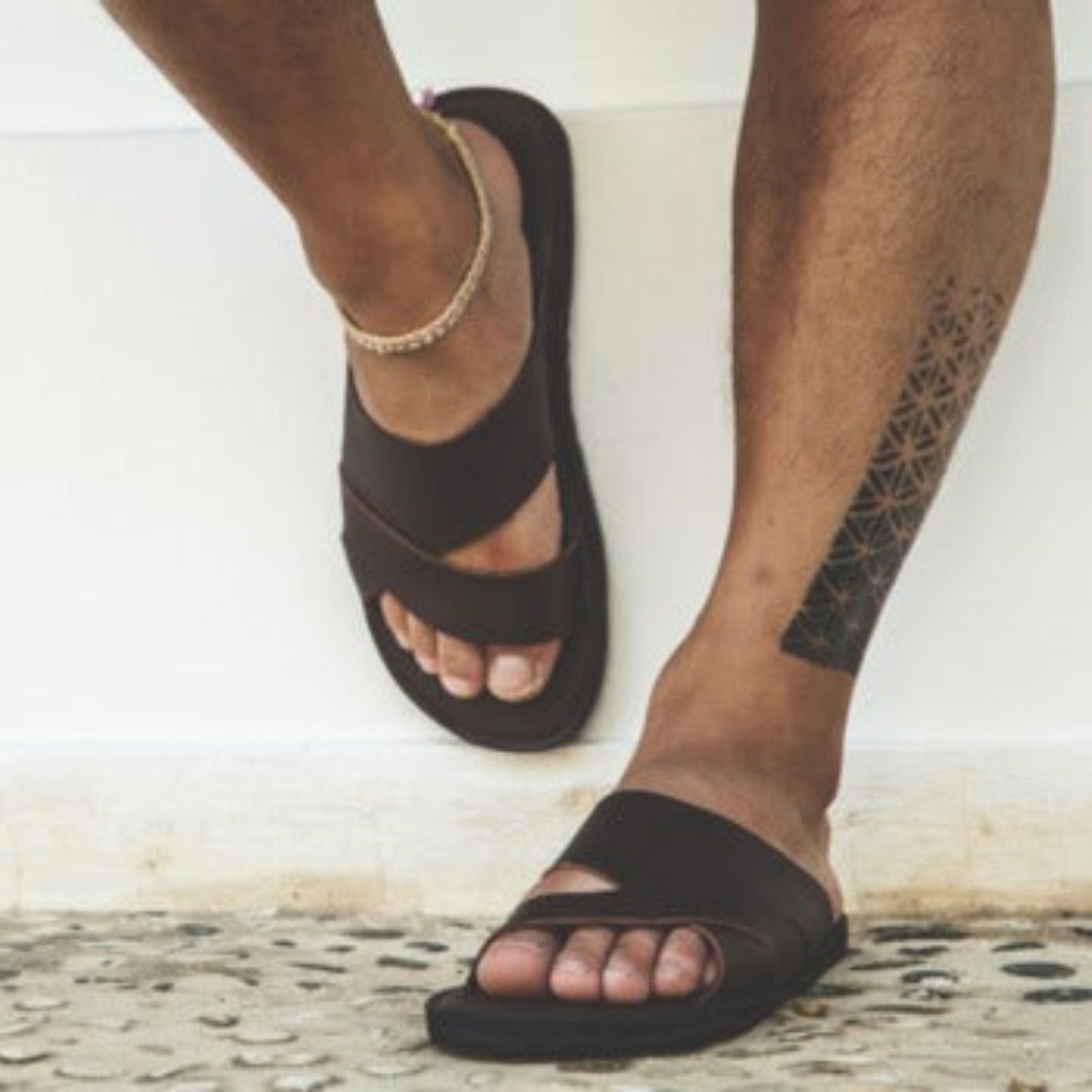 male foot model wearing the Miina Mateo eco leather slide sandal with upcycled tire soles