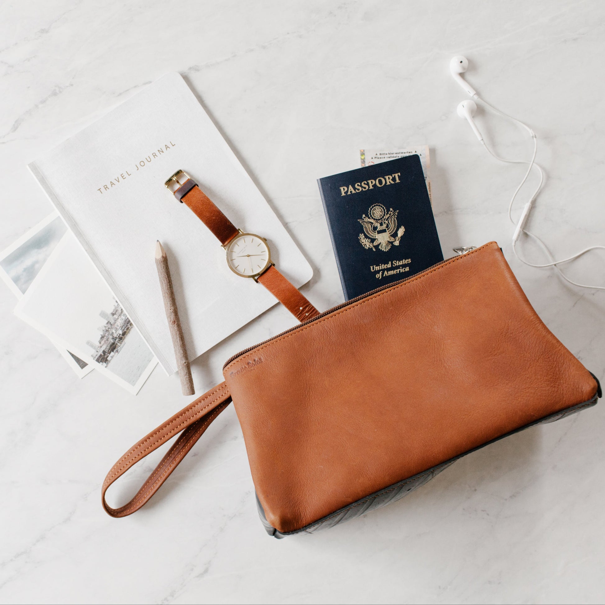The Miina Leather Toiletry Bag laying flat with accessories like a toothbrush, shaving cream, and comb spilling out, showcasing its practicality and storage capacity.