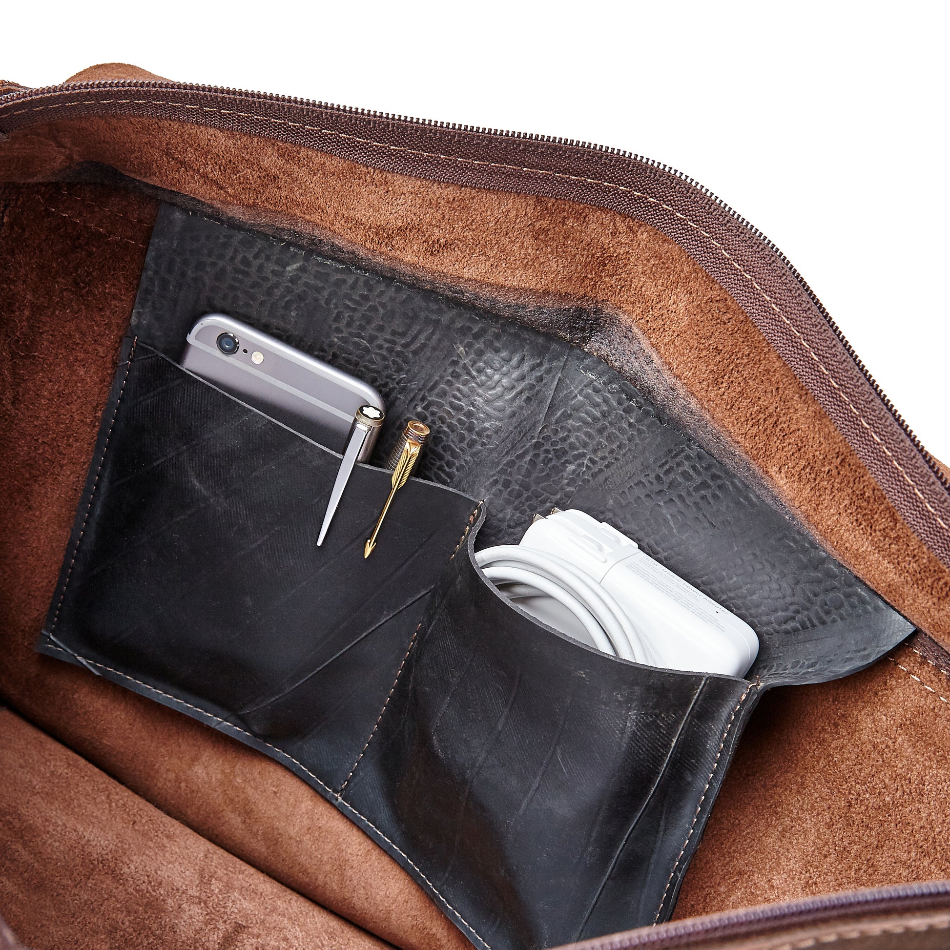 Interior of the Miina Leather Messenger Bag featuring a spacious pocket designed to hold a phone, pen, and charger, organized for convenience.